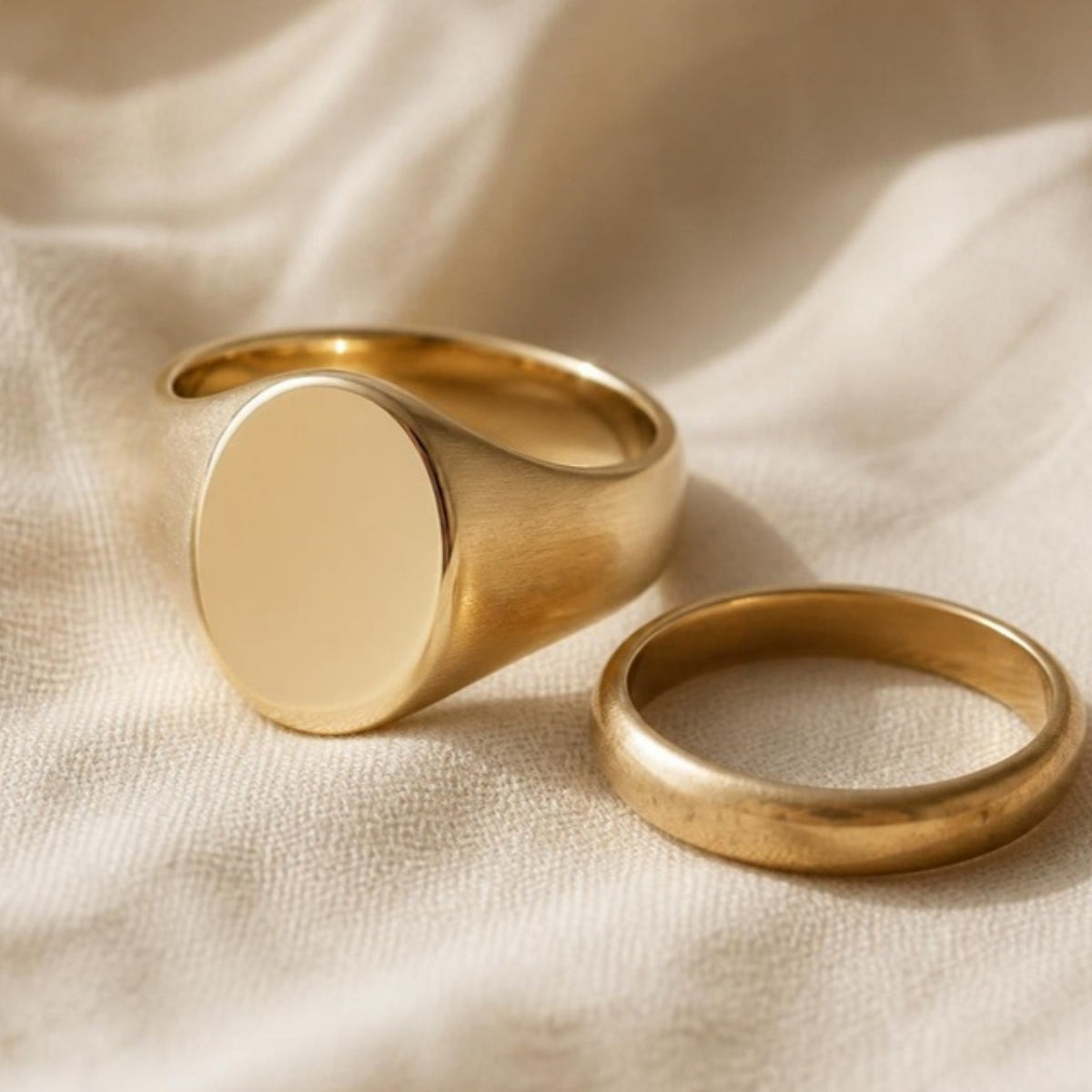 Solid 14k gold oval signet ring beside an old worn gold wedding band
