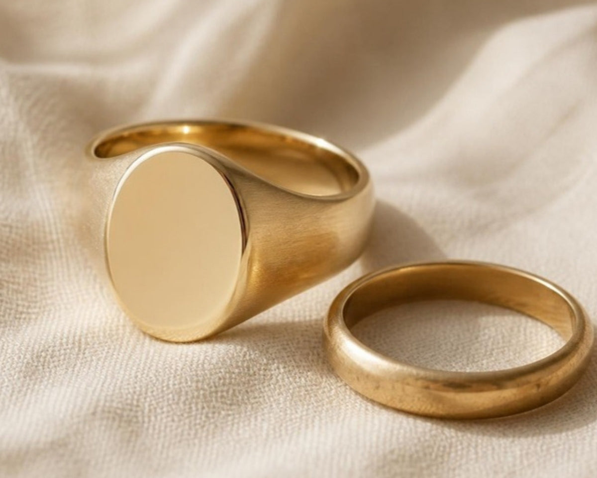 Solid 14k gold oval signet ring beside an old worn gold wedding band